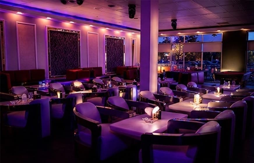 Lounge dining room with violet uplighting and curated table service